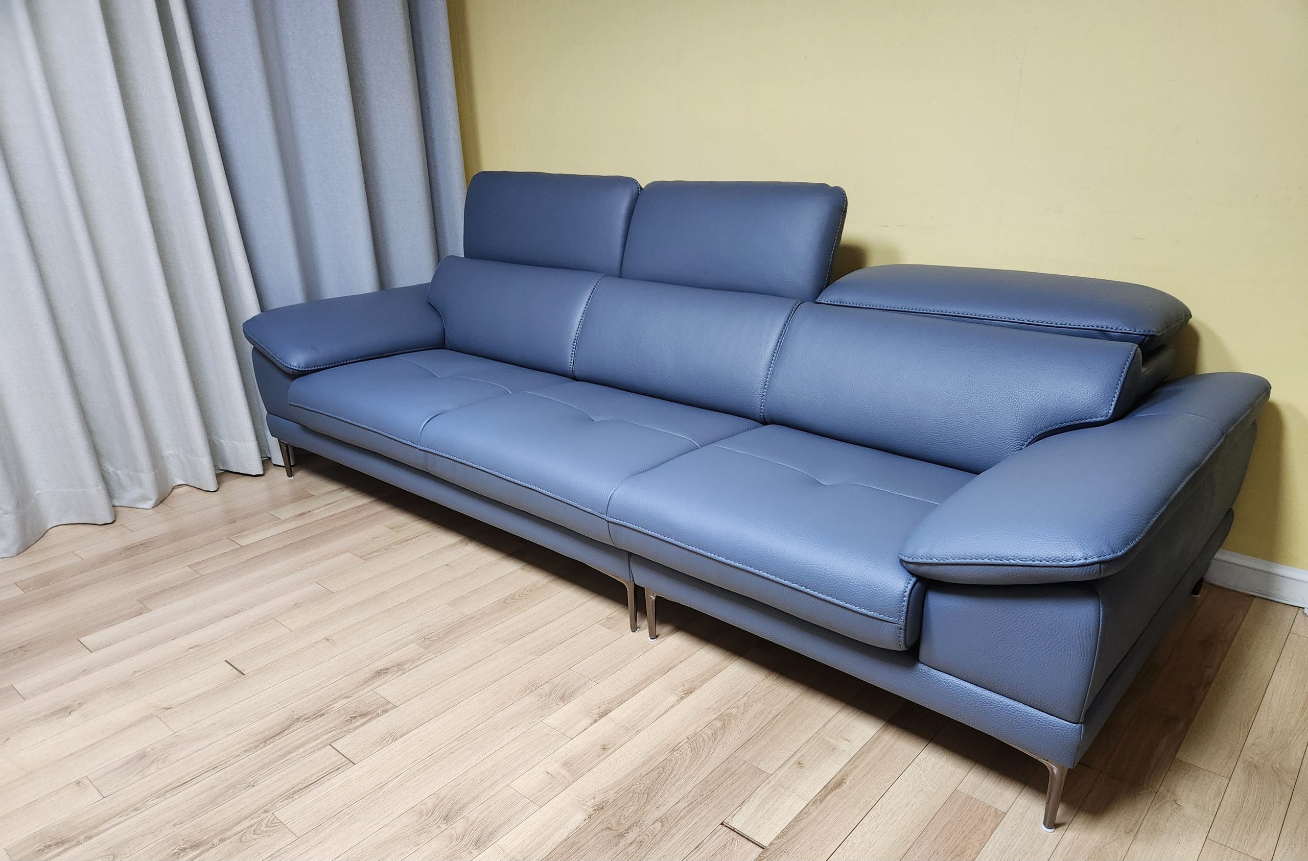 Sofa băng SELECTA 3.5 chỗ màu xanh xám nhạt, chụp từ góc bên, cho thấy chiều sâu của đệm ngồi và độ cong nhẹ của tay vịn…