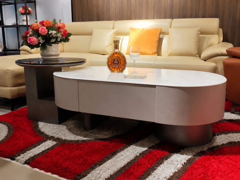 Bàn trà đôi LUNEA trong bối cảnh phòng khách sang trọng với sofa da màu kem, thảm đỏ họa tiết nổi bật. Trên bàn có bình ho…