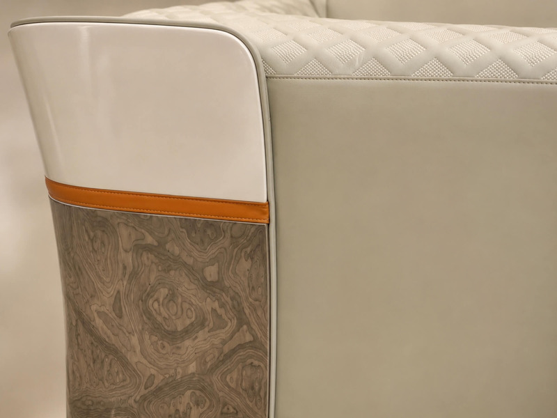 Cận cảnh phần hông ghế sofa IMPERIO SFGD52-123, với da màu be, viền da nâu cam và ốp gỗ vân đá. Góc chụp này làm nổi bật s…