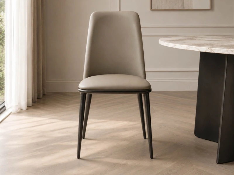 Một chiếc ghế ăn CASSIA màu xám be được chụp cận cảnh từ phía trước, làm nổi bật đường cong mềm mại của lưng ghế và phần đ…