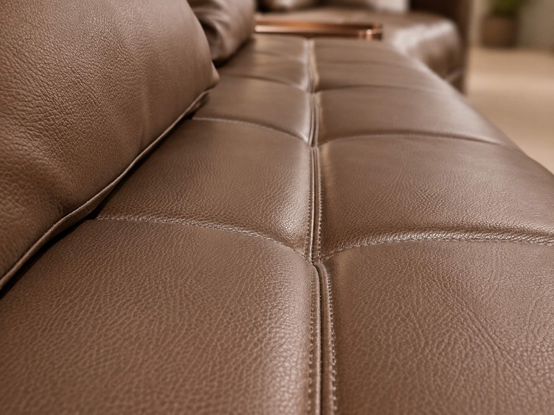 Chi tiết bề mặt da bò và đường may ngang trên đệm ngồi của sofa SF8132, tạo cảm giác êm ái và sang trọng. Các đường may đề…