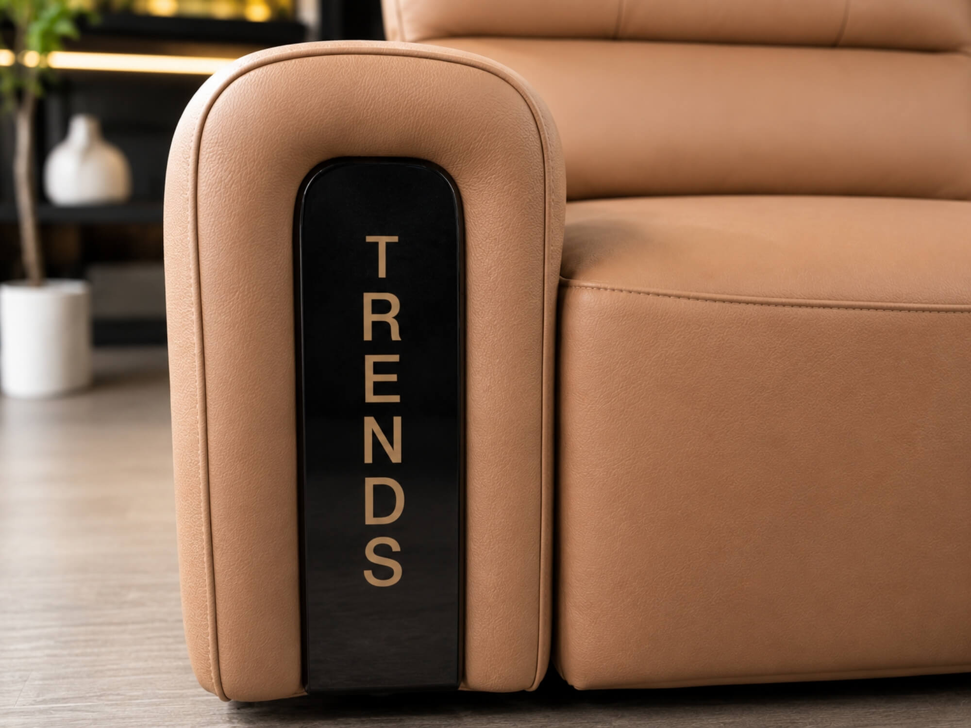 Cận cảnh tay vịn của ghế sofa chỉnh điện SF8144 màu nâu be, với chi tiết trang trí màu đen bóng có chữ "TRENDS" màu vàng n…