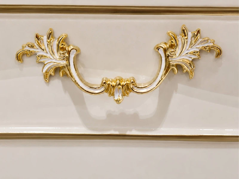 Hình ảnh cận cảnh tay nắm ngăn kéo của kệ tivi SAVOY 2M2. Tay nắm được làm từ kim loại mạ vàng với họa tiết lá cây uốn lượ…