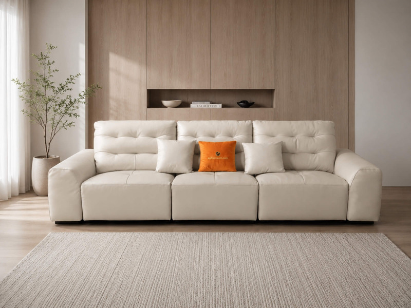 Sofa băng điện AUREO màu kem nhạt được chụp chính diện, đặt trong phòng khách phong cách tối giản. Tường ốp gỗ và thảm trả…