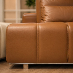 Góc chụp cận cảnh phần chân sofa và sự chuyển tiếp giữa hai khối màu kem và nâu da bò. Thiết kế liền mạch, chất liệu da ca…