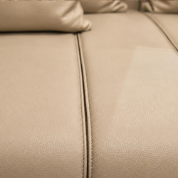 Cận cảnh bề mặt da màu kem của sofa với đường may chỉ nổi bật, thể hiện sự tỉ mỉ trong từng chi tiết sản phẩm. Chất liệu d…