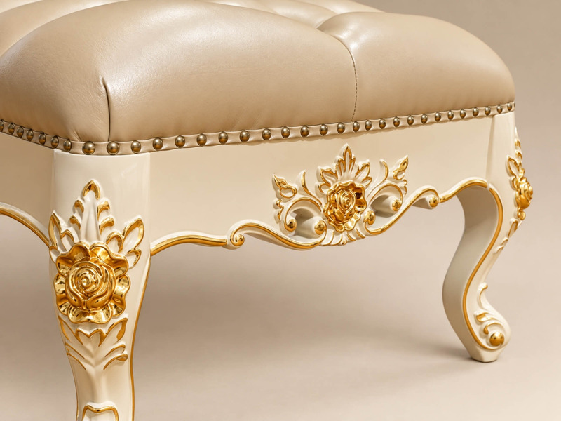 Cận cảnh chân ghế đôn sofa Élysée màu trắng ngà với đường cong mềm mại và các chi tiết chạm khắc hoa văn mạ vàng tinh xảo…