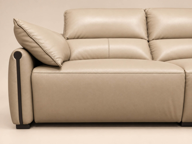 Cận cảnh phần đệm tựa lưng phồng và tay vịn bo tròn của ghế sofa COCOON màu be nhạt. Bề mặt da bò tự nhiên có độ bóng nhẹ…