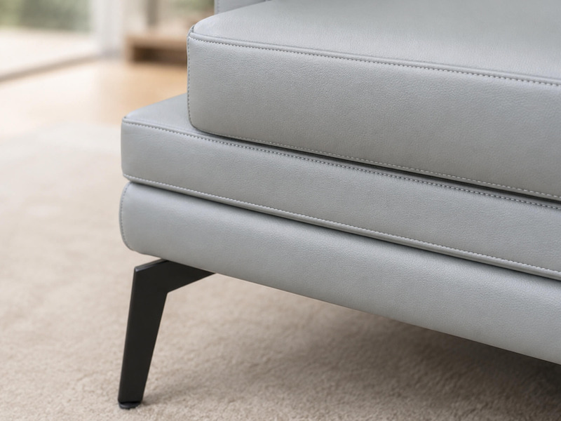 Ảnh cận cảnh góc tựa lưng và tay vịn của ghế sofa LEXINGTON E005, cho thấy đường may tinh xảo trên lớp da màu xám nhạt. Ch…