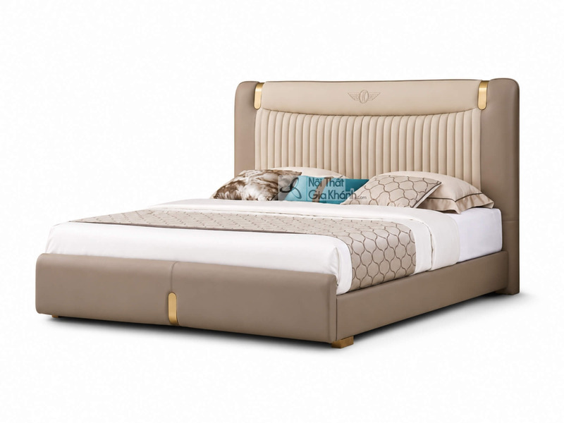 Giường ngủ WINGA Luxury GIQF285-18 chụp chính diện hơi chếch, nổi bật với đầu giường bo cong bọc da màu trà sữa, các đường…