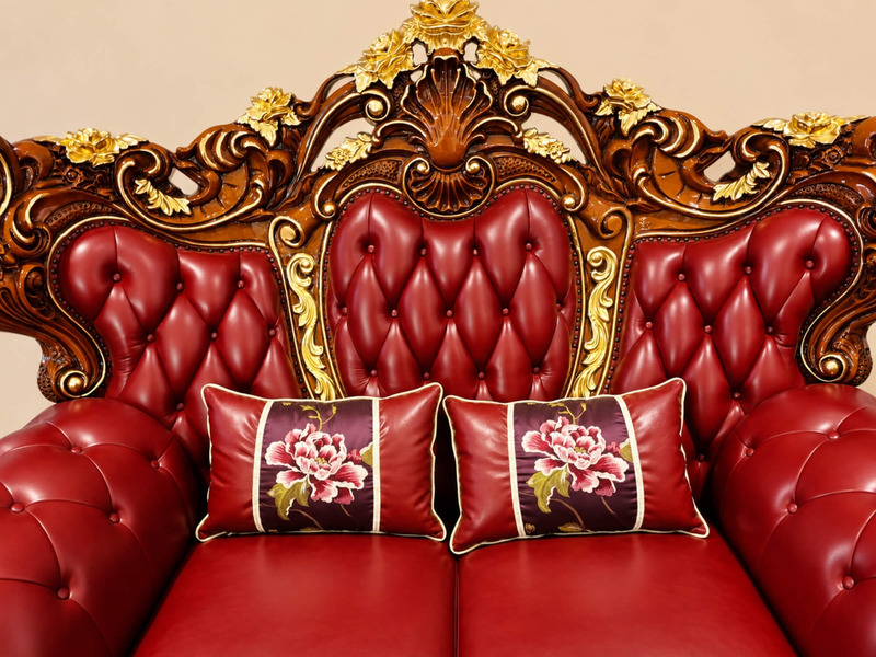 Chi tiết phần tựa lưng và tay vịn của sofa băng dài, chụp cận cảnh từ góc hơi nghiêng. Da bò màu đỏ đô được rút múi đều đặ…