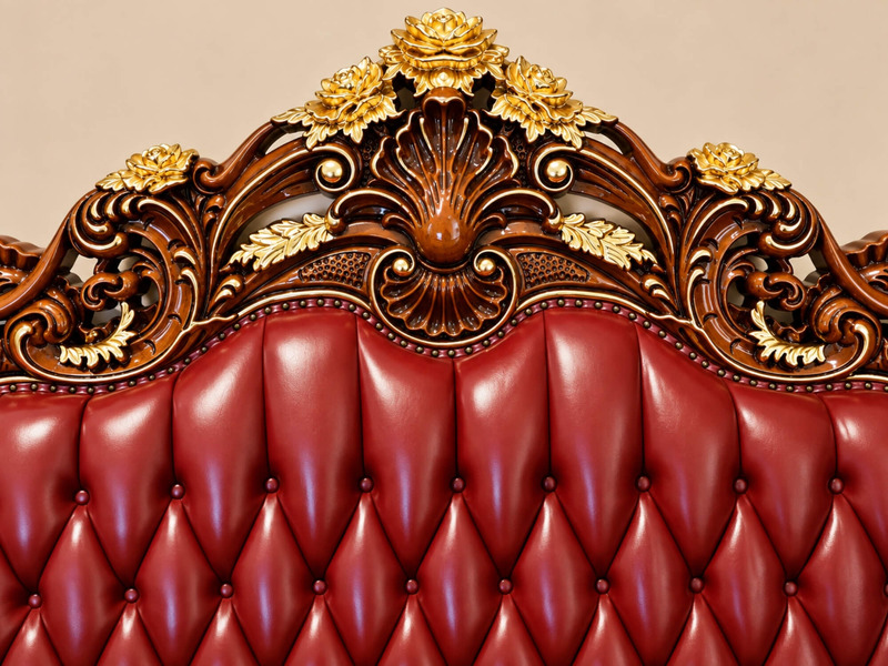 Góc cận đỉnh lưng tựa của sofa CRIMSON EMPEROR, nổi bật với hoa văn chạm khắc hình lá và hoa mạ vàng trên nền gỗ gõ đ…