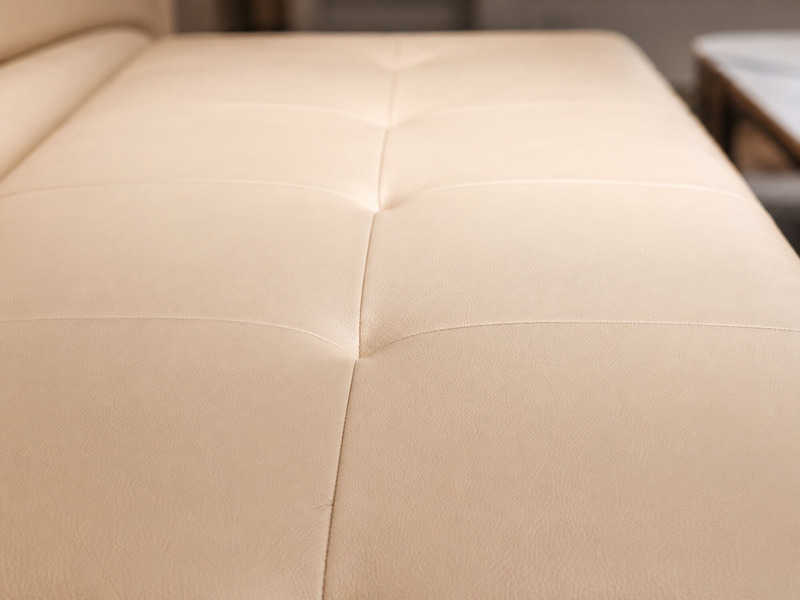Cận cảnh bề mặt đệm của sofa giường Lamia C1004 màu kem. Chất liệu bọc mịn màng, kết hợp với các đường may chần múi tinh x…