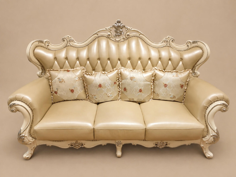 Ghế sofa băng ba VALERION được chụp chính diện, tập trung vào sự êm ái của đệm da màu kem và các gối tựa lưng nhỏ họa tiết…