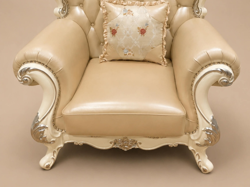 Cận cảnh phần chân và tay vịn của ghế sofa đơn VALERION tân cổ điển, bọc da bò màu kem. Khung gỗ sồi tự nhiên chạm khắc ti…