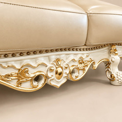 Cận cảnh phần chân ghế và đường viền dưới của sofa VERSALÉON, với các họa tiết chạm khắc dát vàng chạy dọc theo khung gỗ…