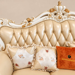 Cận cảnh lưng tựa và gối tựa của sofa băng VERSALÉON, với các đường rút múi đều đặn trên bề mặt da kem. Gối trang trí họa…