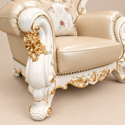 Cận cảnh tay vịn và phần chân ghế của sofa đơn VERSALÉON, với các chi tiết chạm khắc hoa văn dát vàng trên khung gỗ màu ke…