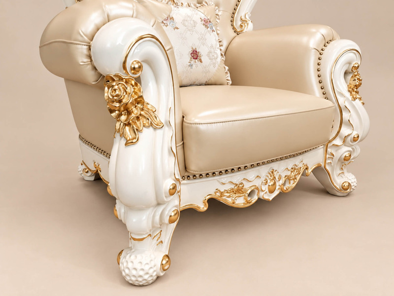 Cận cảnh tay vịn và phần chân ghế của sofa đơn VERSALÉON, với các chi tiết chạm khắc hoa văn mạ vàng trên khung gỗ màu ke…