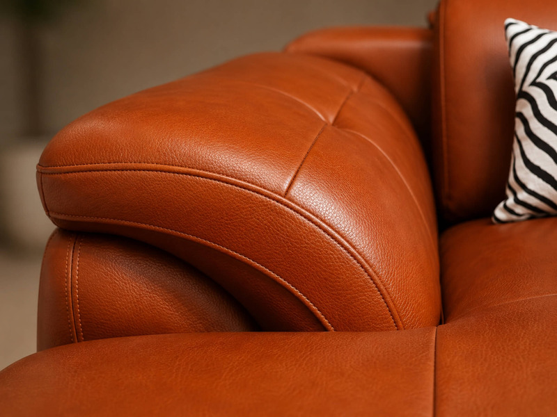 Cận cảnh góc cong của sofa góc màu nâu da bò, làm nổi bật thiết kế ôm sát và đường may chắc chắn. Chi tiết này thể hiện sự…