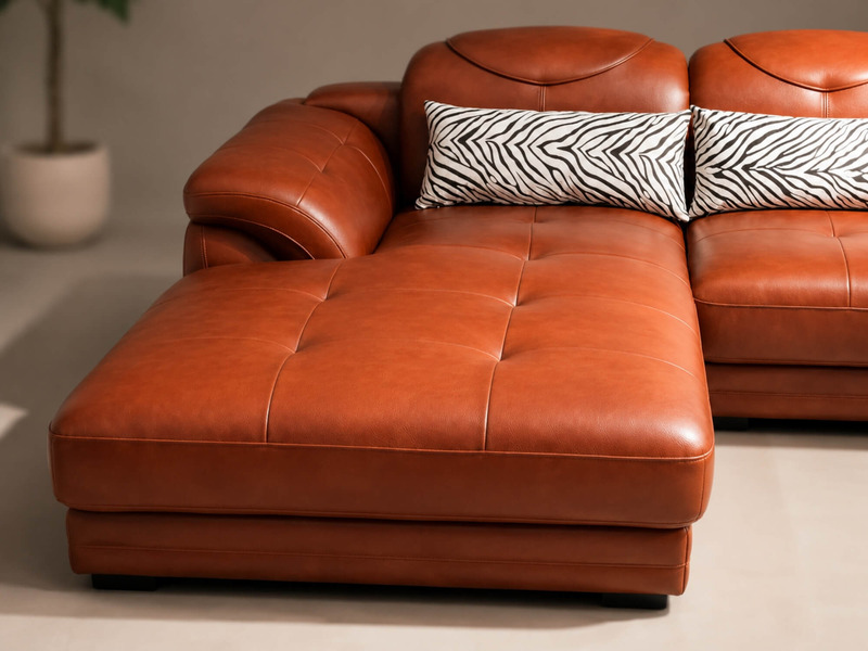 Cận cảnh phần ghế dài (ghế đôn) của sofa góc màu nâu da bò, cho thấy chất liệu da mềm mại và các đường may chần nút tinh t…