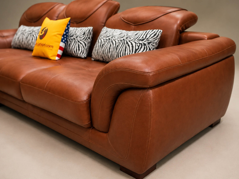 Góc chụp cận cảnh tay vịn và phần đệm ngồi của sofa góc màu nâu da bò, làm nổi bật độ dày của đệm và chất liệu da cao cấp…